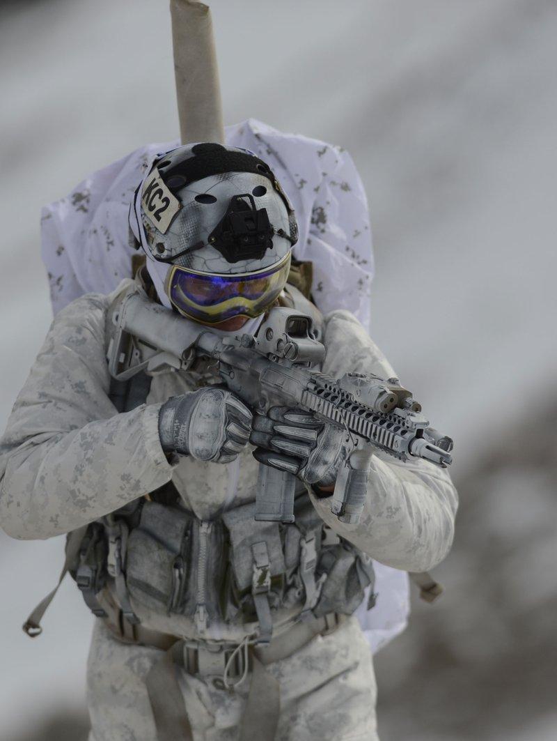 Navy SEAL in white winter camouflage holding a white painted short barreled CQBR with a quad rail, EOTech sight and four prong flash hider