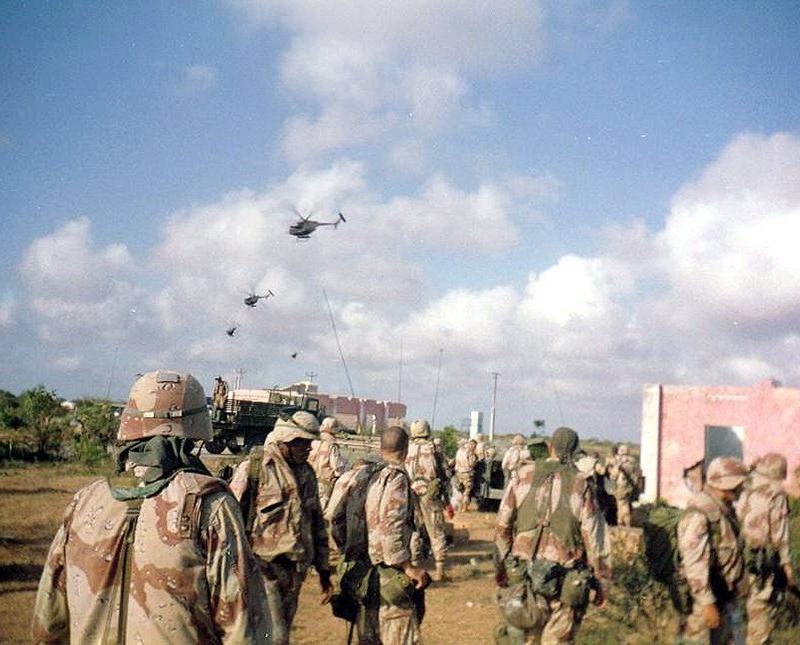 US Army soldiers in desert camouflage watch helicopters flying over Mogadishu on 3 October 1993