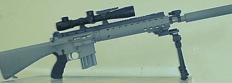 Side profile of an early SPR with a vented free float tube under a full length top rail, a scope, a suppressor, a bipod and a fixed rifle stock