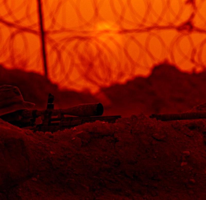 Army Special Forces soldier prone behind a scoped, suppressed Mk12 at sunset with concertina wire behind, Rawah, Iraq, 2007